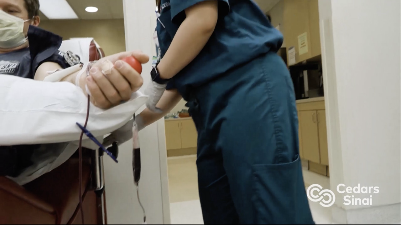 image description: patient laying on table while nurse extracts blood from their arm.